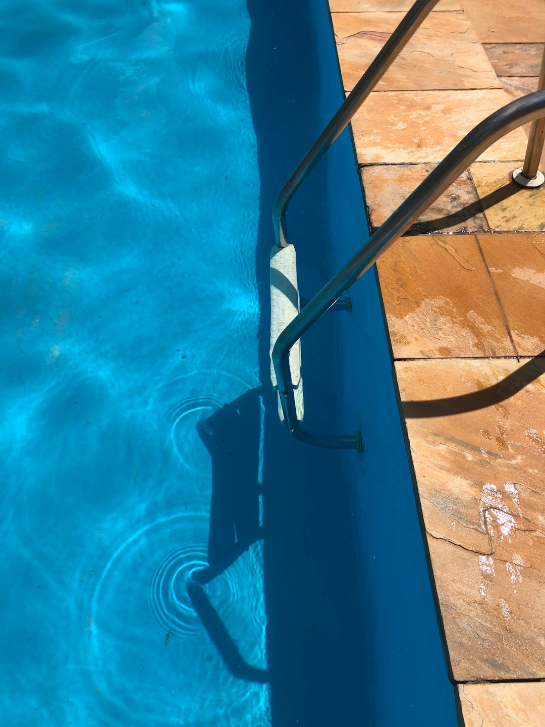 a-blue-swimming-pool-with-a-metal-hand-rail-foaewyuzwia