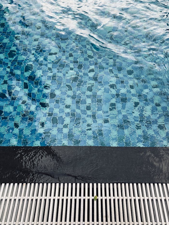 A close-up view of clean blue swimming pool water with ripples and a tiled floor.