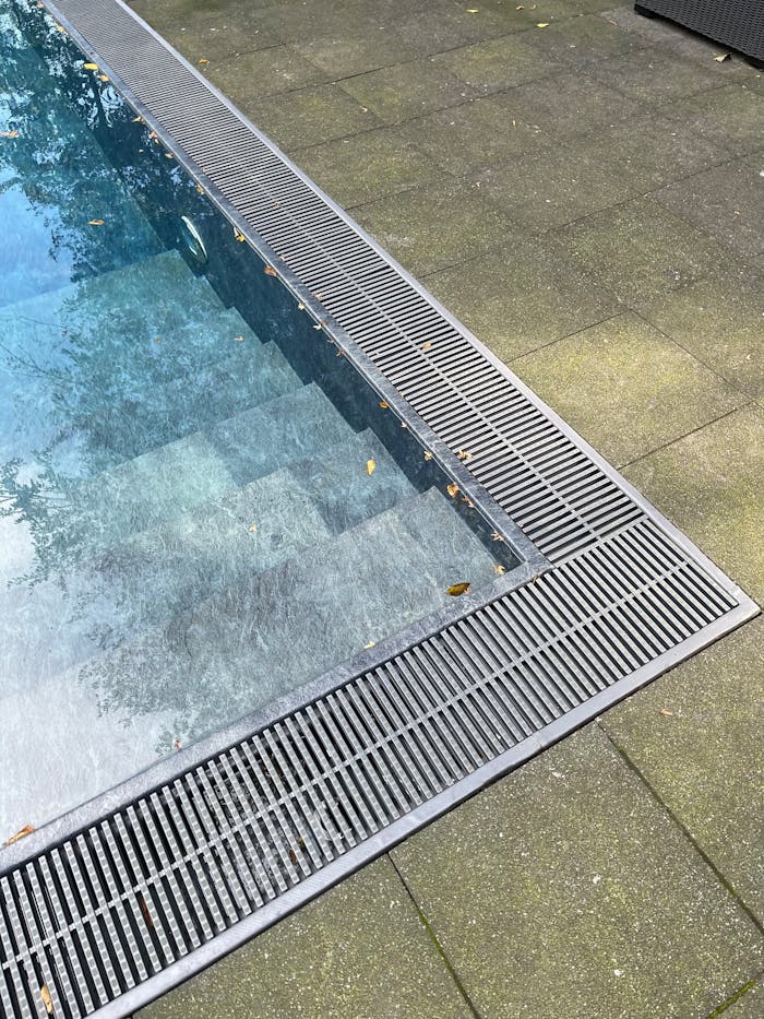 A detailed view of a swimming pool edge with modern design elements, located outdoors.